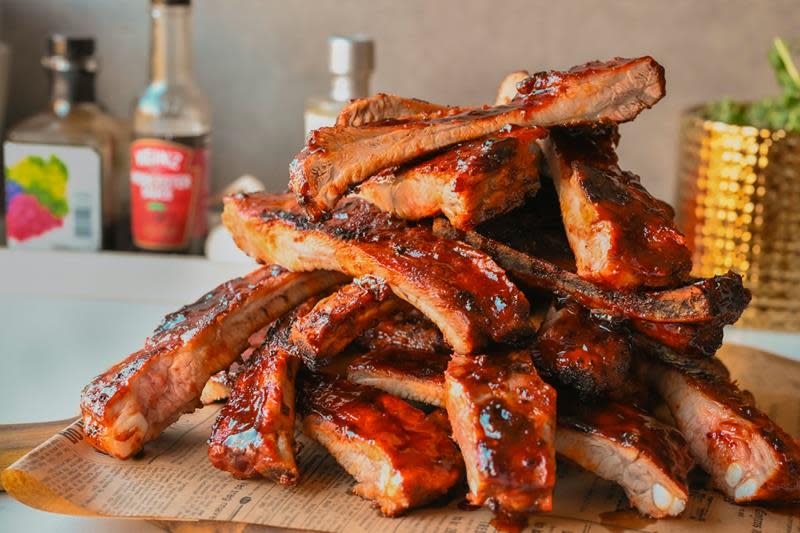 Spareribs delt opp og servert på fat, med krydderflasker i bakgrunnen.