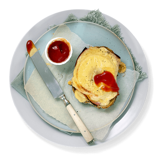 Ostesmørbrød Hawaii med skinke og ananas, servert på lys blå tallerken, med et lite glass ketchup.
