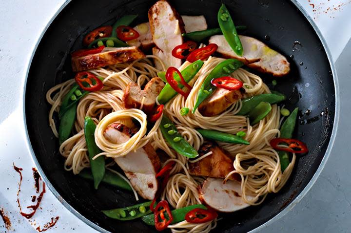 Hoisin kyllingwok med kyllingfilet, nudler, sukkererter, fersk chili og hoisinsaus i wokpanne. Hvit bakgrunn.