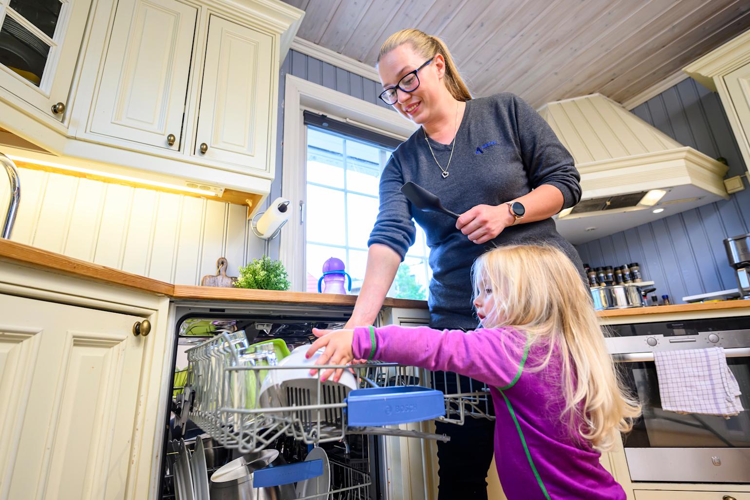 Mor og barn fyller oppvaskmaskin