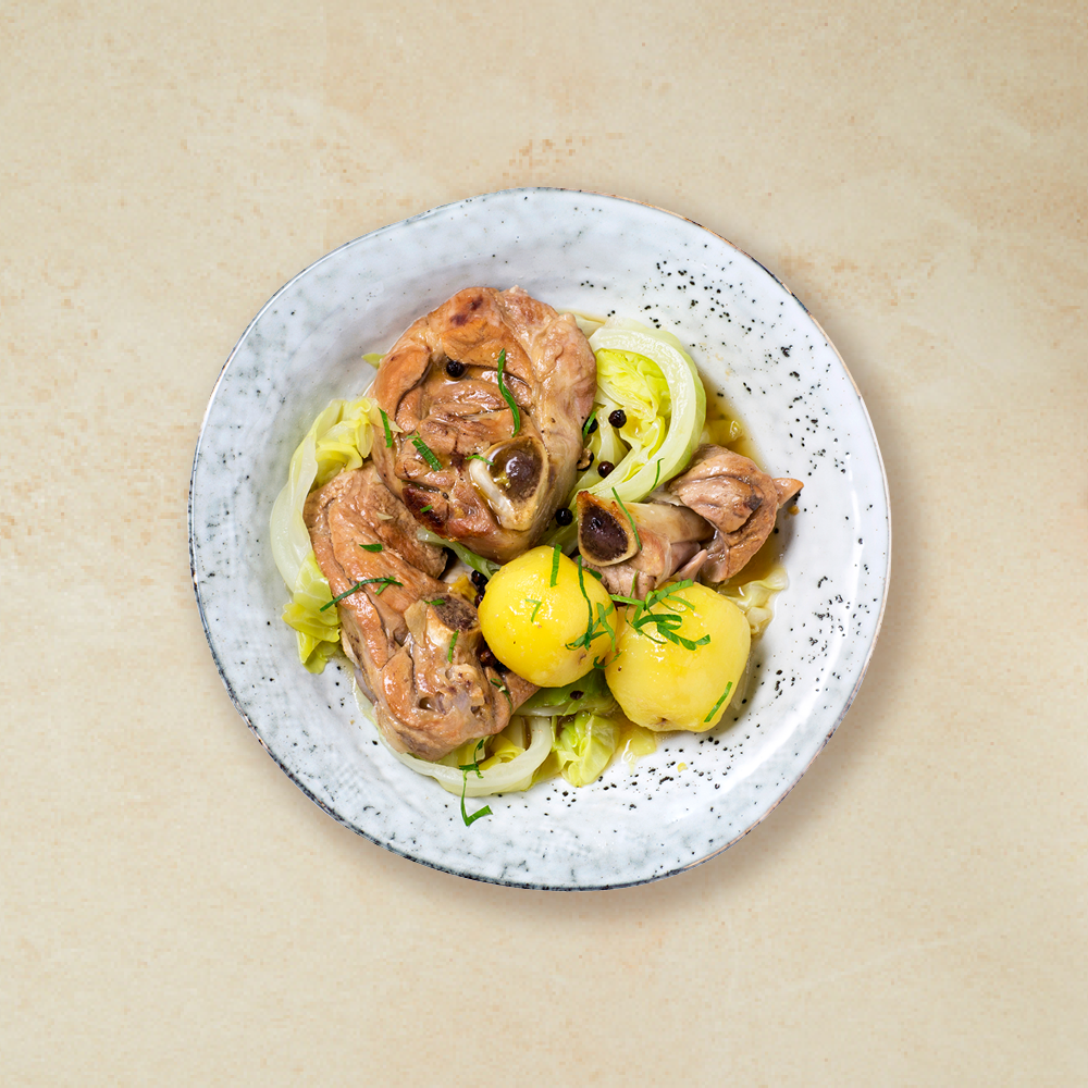 Lettvint fårikål med lam, kål, kokt potet og hele pepperkorn servert i lys skål på hvit bakgrunn.