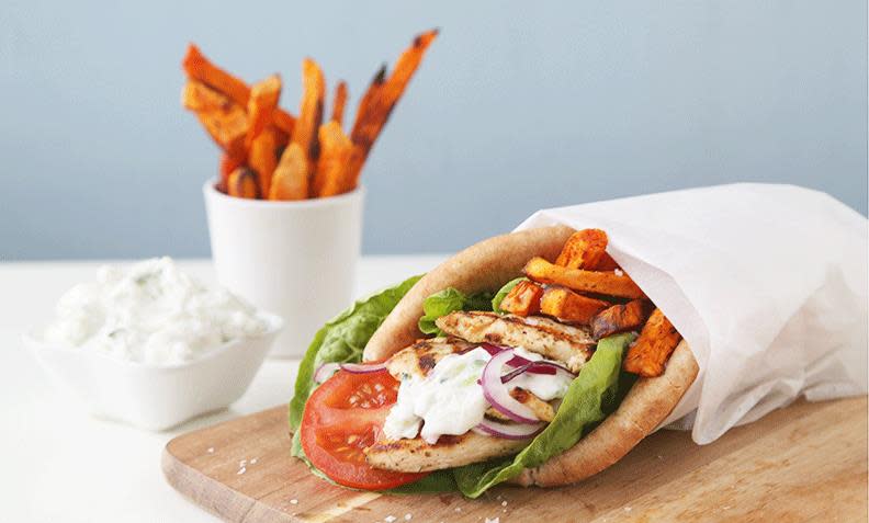 Kyllingyros med tzatziki, tomat, salat og søtpotetchips på en fjøl servert med tzatziki og søtpotetchips på siden.