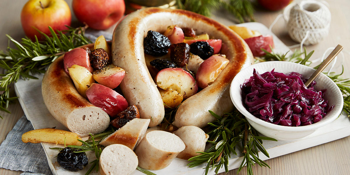 Stekt julepølse oppskåret og hel på serveringsfat, med rødkål i skål ved siden av