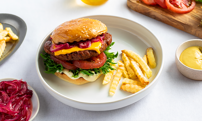 Vegetarburger med grønnsaker og ost, servert på en hvit tallerken med fries og karamellisert løk