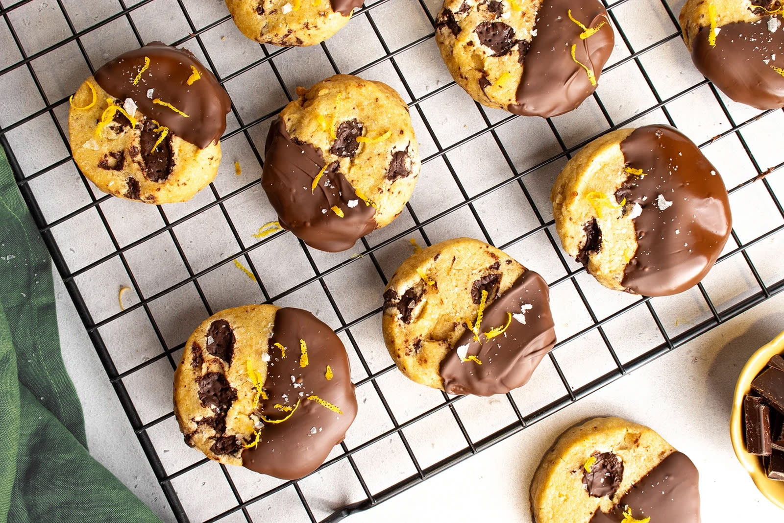 Julekjeks med appelsin og sjokolade dyppet i sjokolade og servert på svart kjølerist med grønn linserviett ved siden av.