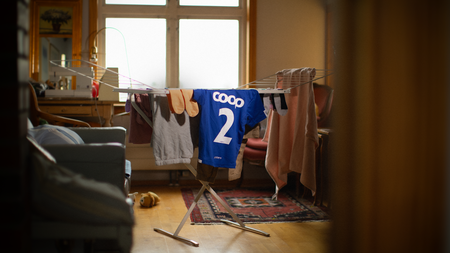 Coop-drakt henger på tørkestativ