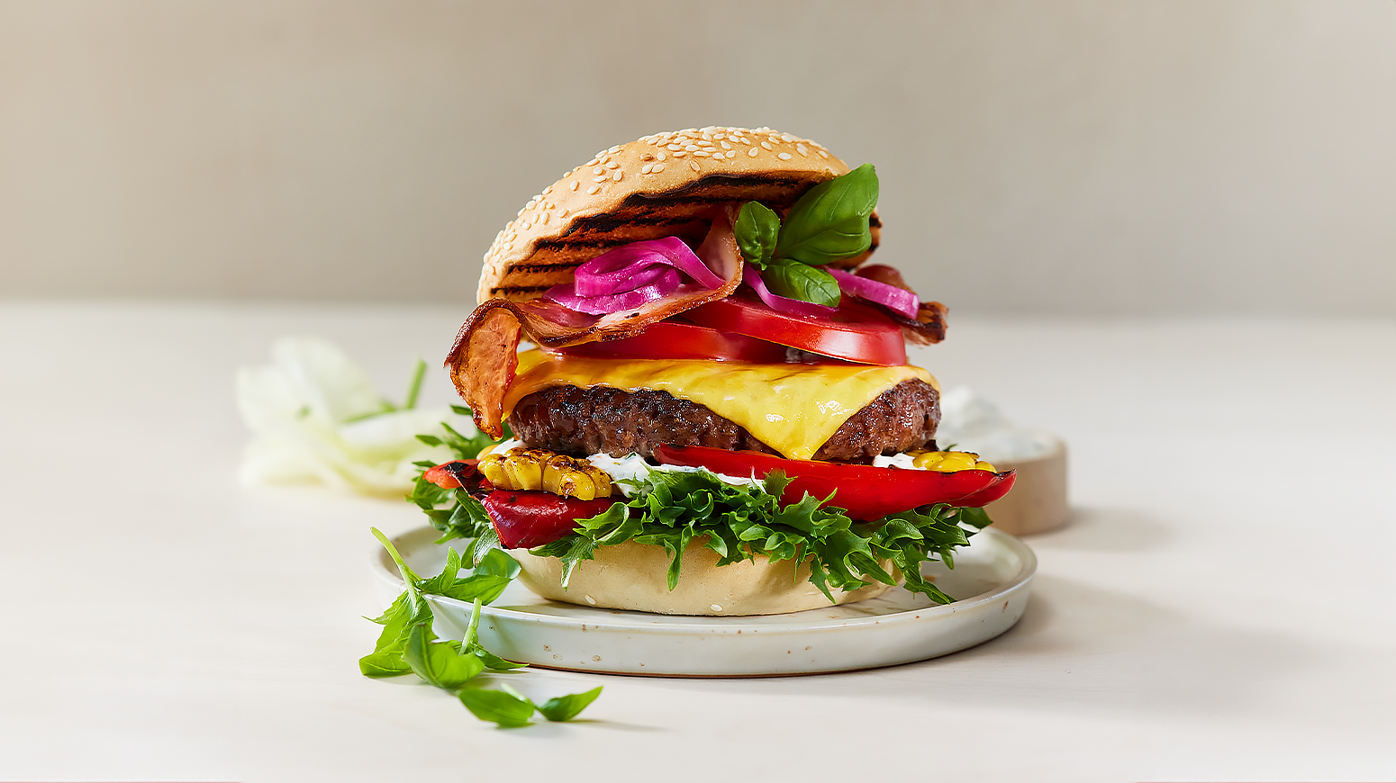 Beefy cheeseburger med bacon, ost, tomat, syltet rødløk, grillet mais og paprika.
