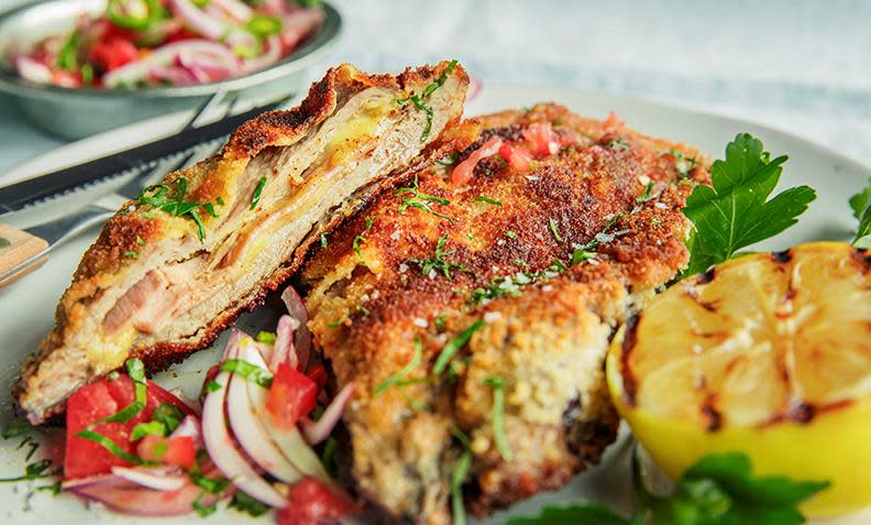 Kotelett Cordon Bleu - fylte koteletter med ost og skinke, servert på middagstallerken med grillet sitron, tomatsalat og ferske urter.