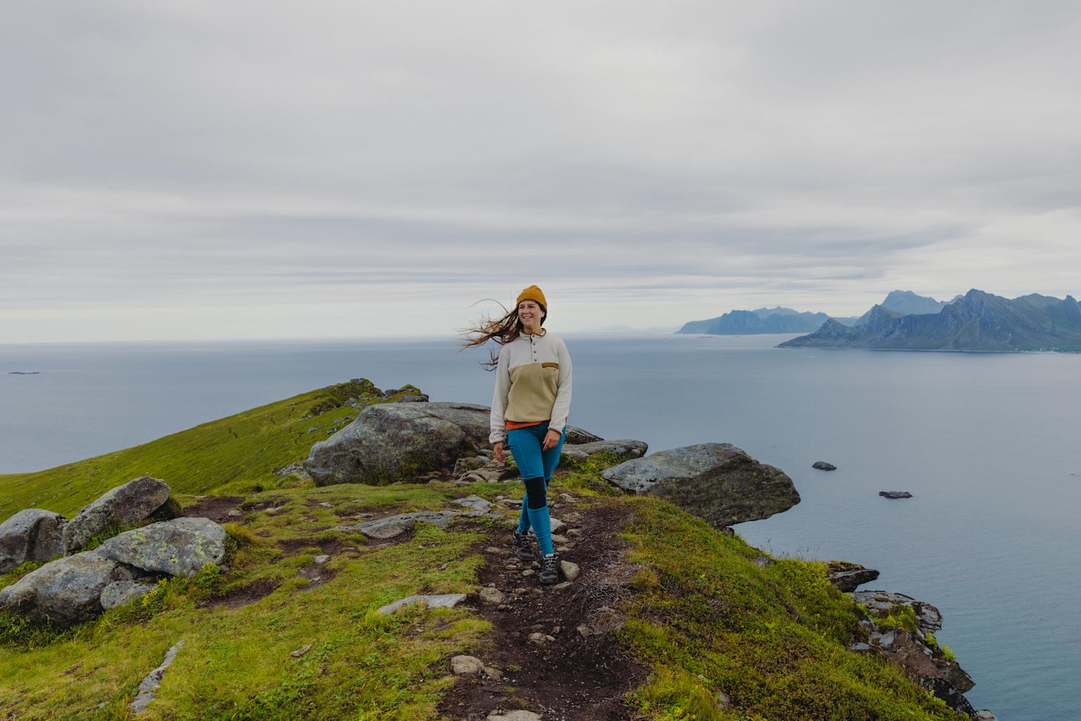 Kvinne på toppen av et fjell med hav i bakgrunnen